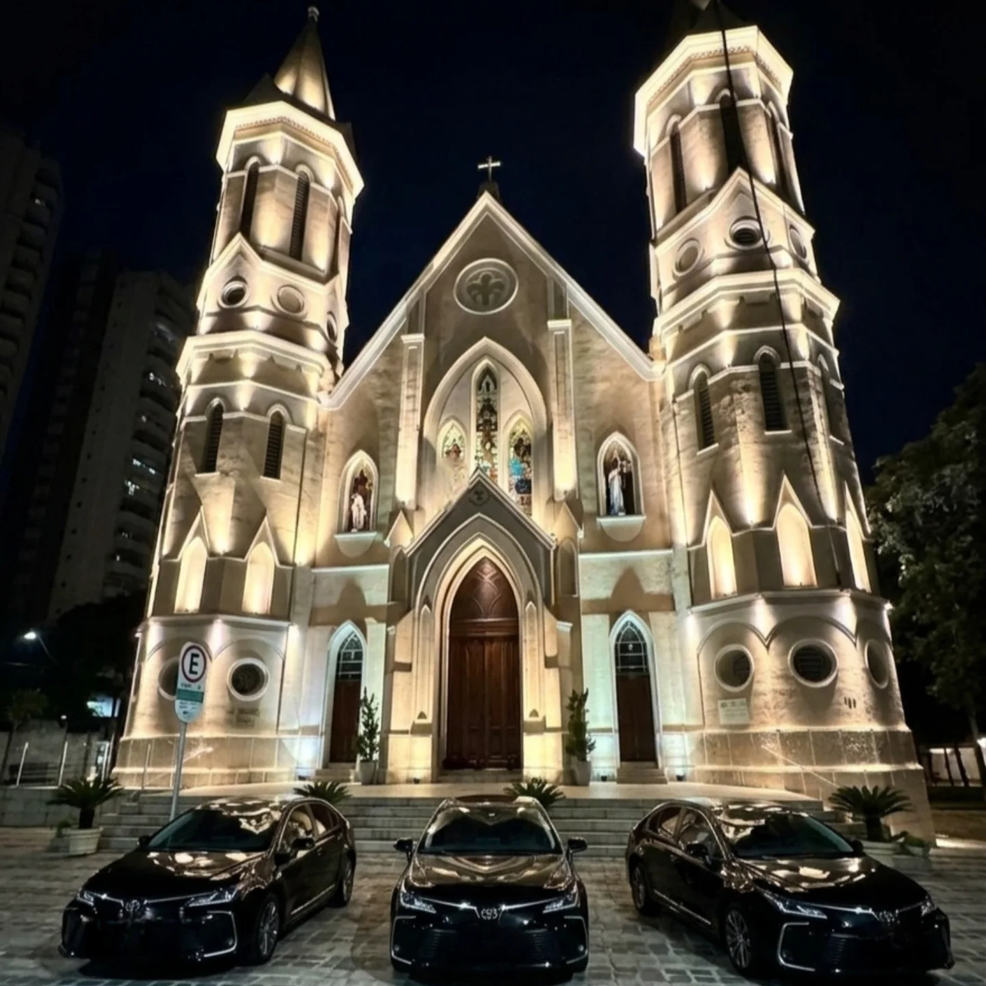 Veículos executivos em frente a uma igreja iluminada